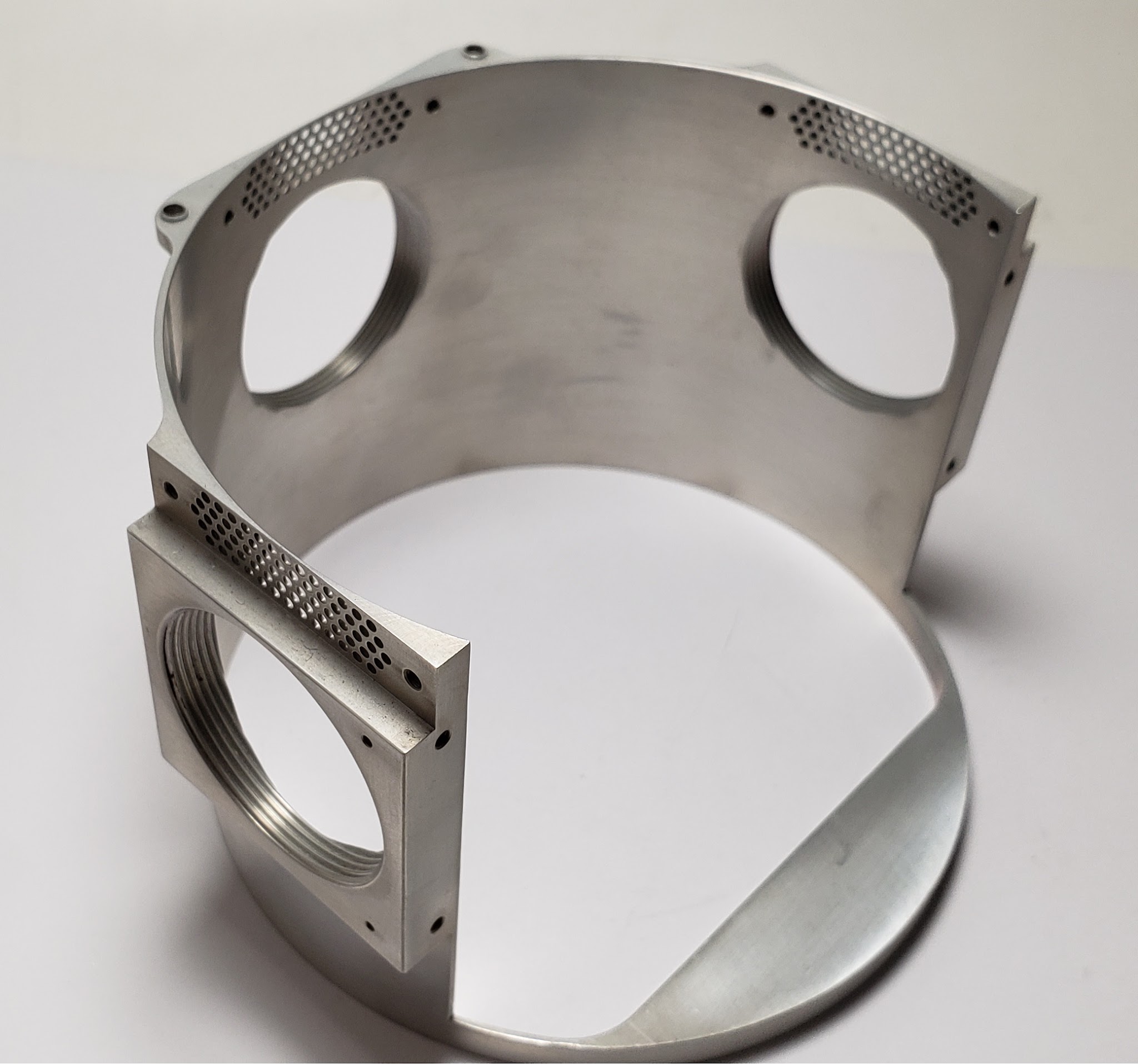 Machined aluminium cylindrical housing with threaded ports and drilled vent arrays