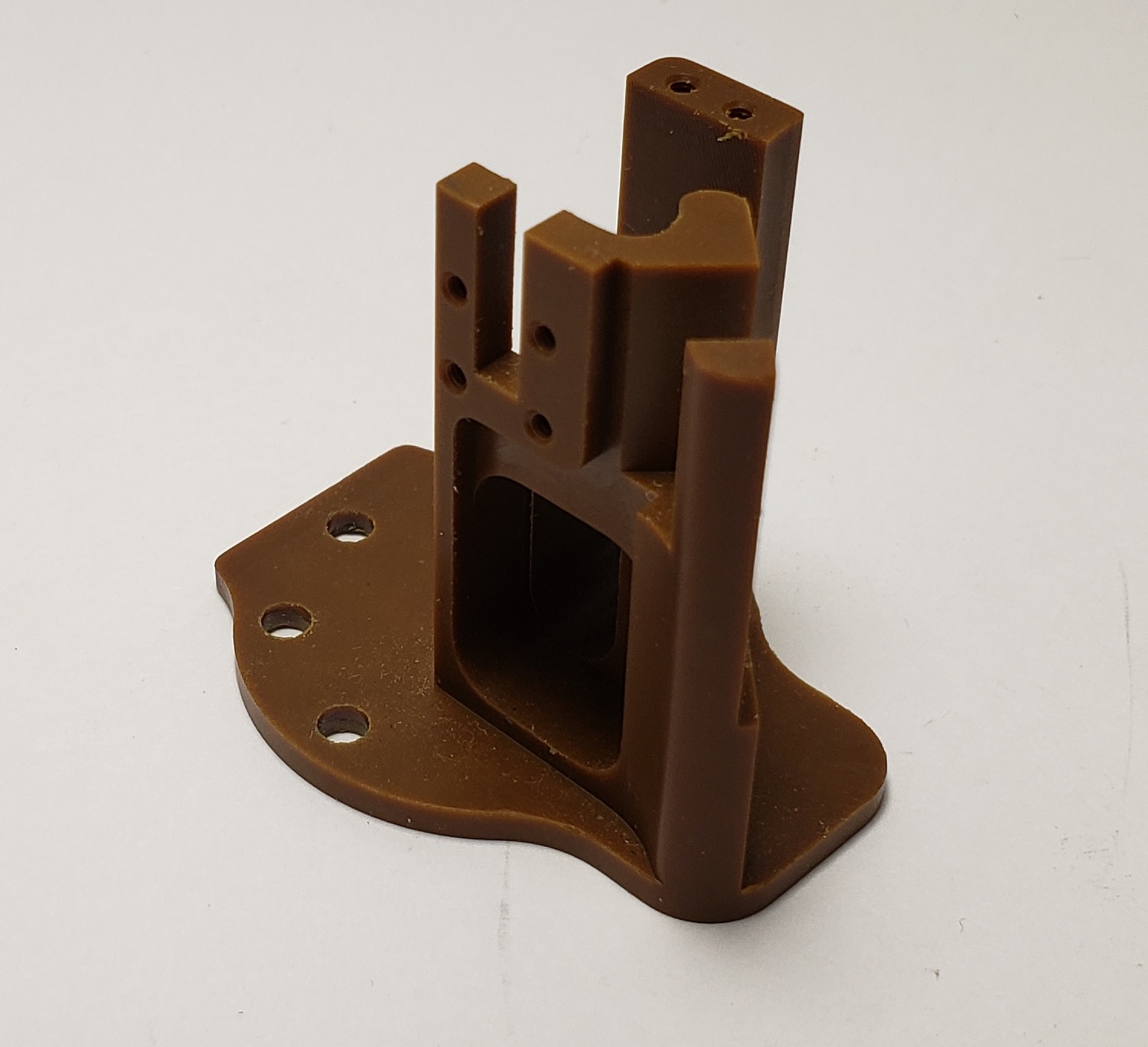 Machined engineering plastic bracket with a contoured base plate and drilled mounting holes